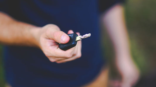 Hand holding a car key outdoors