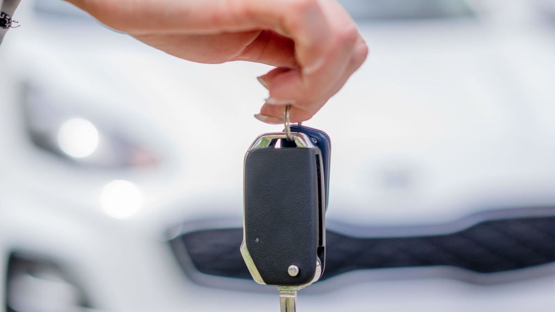 Hand holding a car key by a vehicle