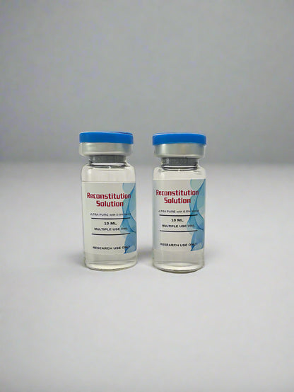 Three vials with blue caps and labels in front of a black box with gold text on a white background